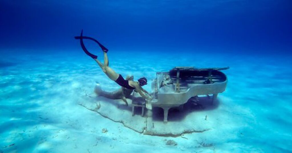 Charter yacht guest playing a submerged piano at Musha Cay in the Bahamas