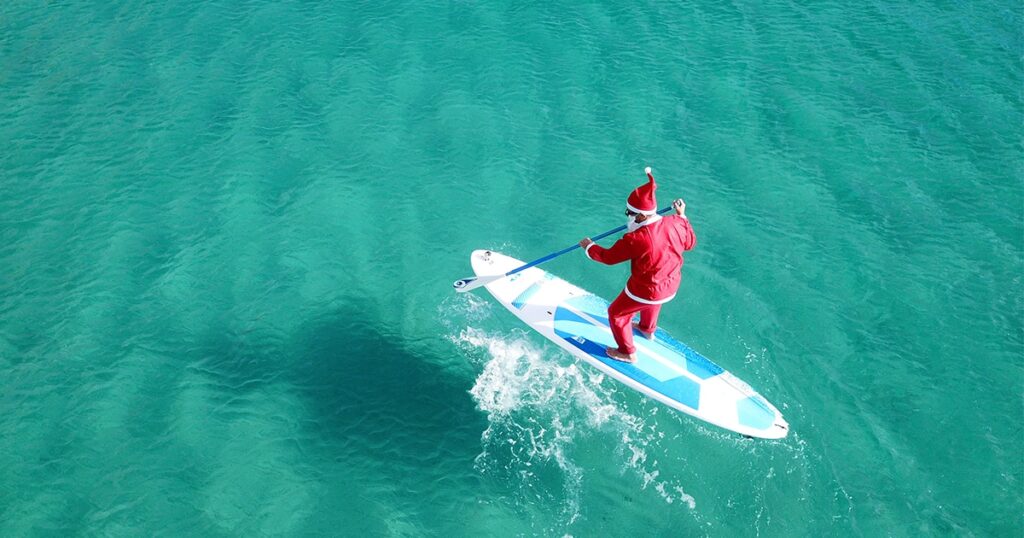 Charter yacht guest dressed as Santa on a stand up paddle board in the Caribbean